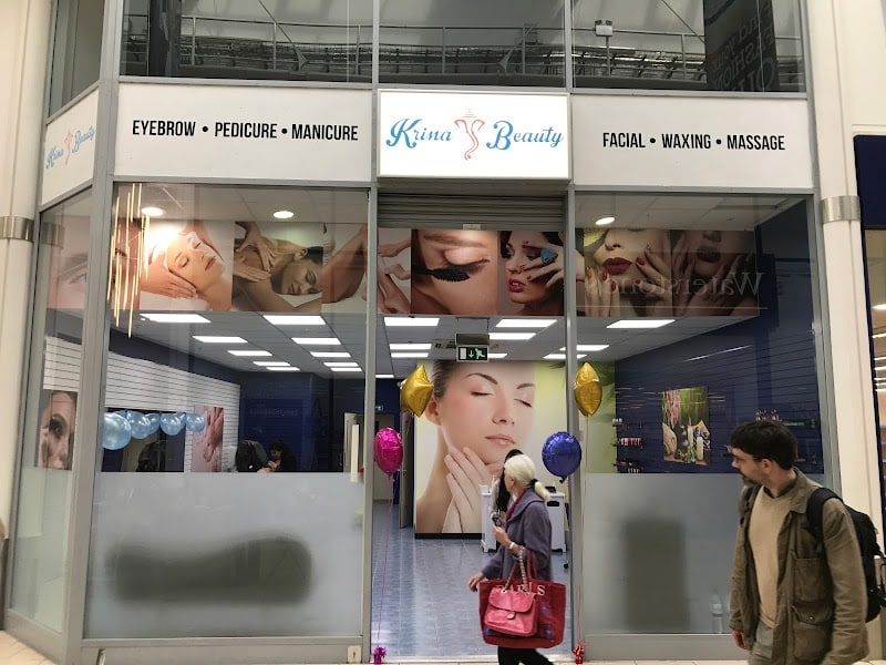Beauty salon storefront with glass windows, posters, and people walking by.