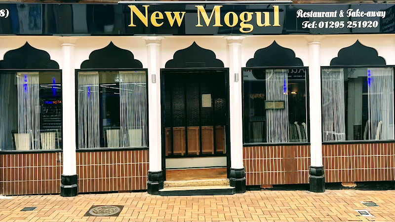 Storefront of New Mogul Indian restaurant with black and white decor and phone number visible.